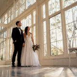 Couple beneath soft orangery window light